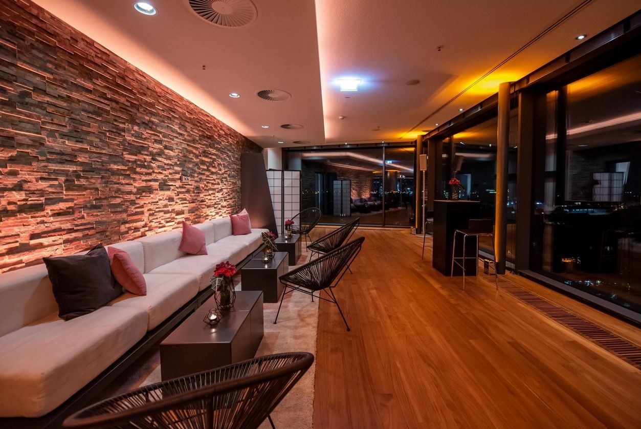 Moderne Lounge mit Holzfußboden, gemütlichen Sitzgelegenheiten und stimmungsvollem Licht.