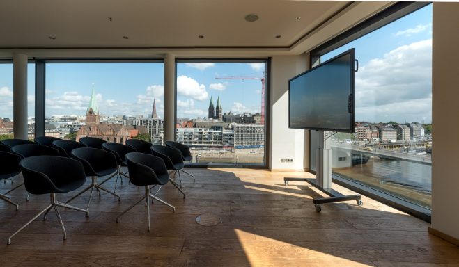 Moderne Besprechungsraum mit Stadtblick und einem großen Bildschirm.