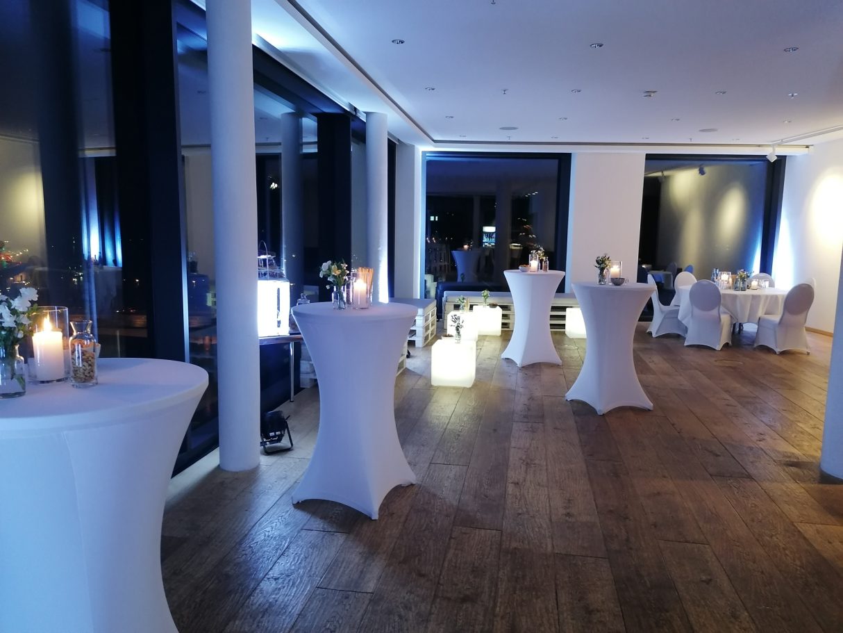 Eleganter Veranstaltungsraum mit Stehtischen und sanfter Beleuchtung.