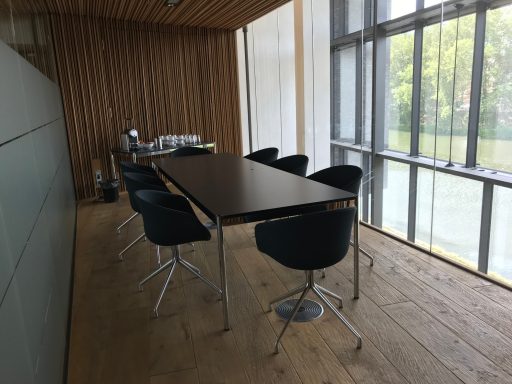 Ein moderner Konferenzraum mit einem langen Tisch und schwarzen Stühlen.