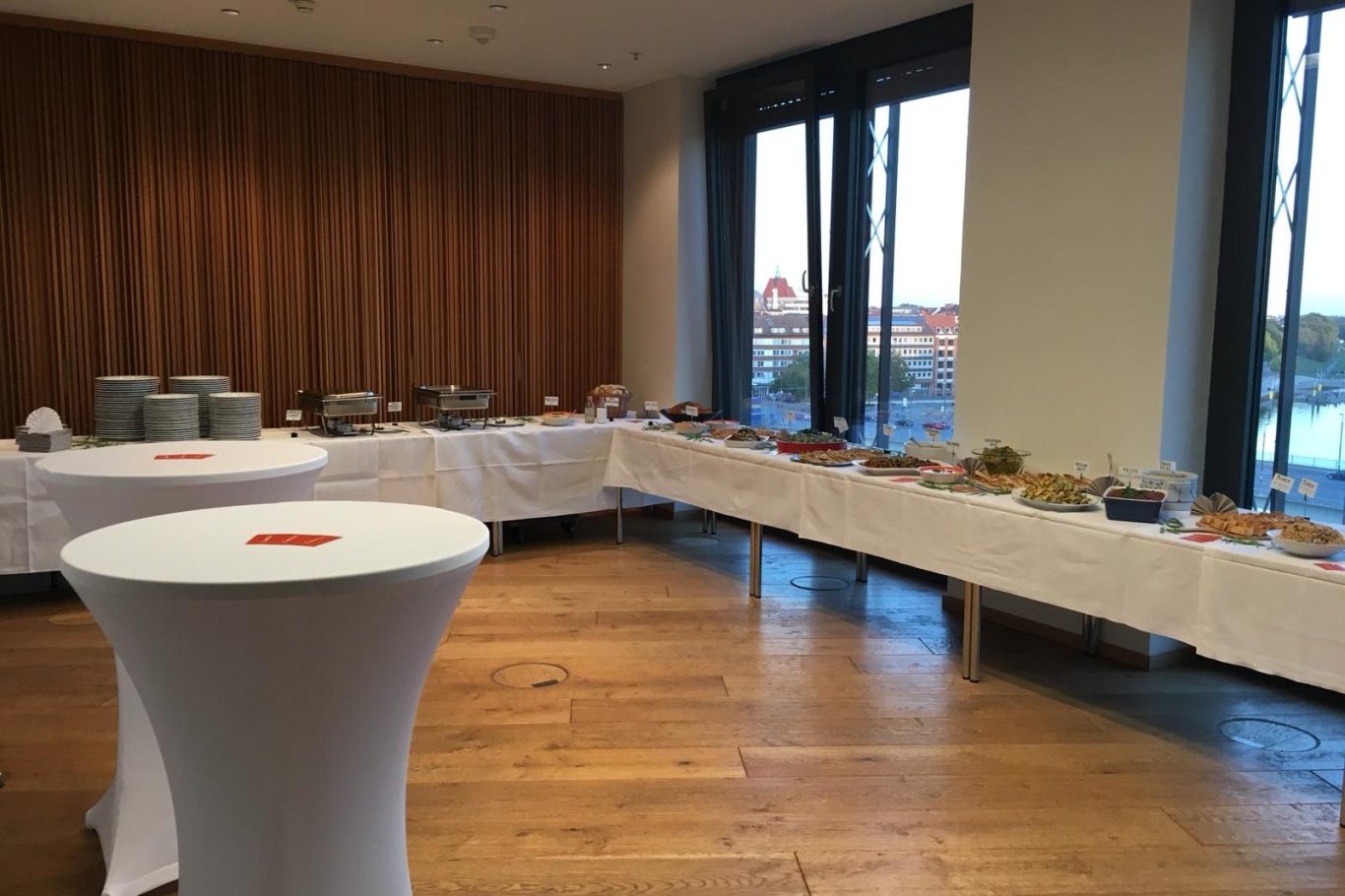 Buffet mit verschiedenen Speisen und Getränken in einem modernen Veranstaltungsraum.