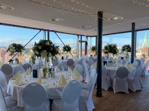 Elegant Veranstaltungsraum mit runden Tischen und Blumendekoration.