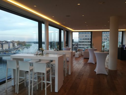 Moderne Veranstaltungsräume mit Tischen und Blick auf Wasser und Stadt.