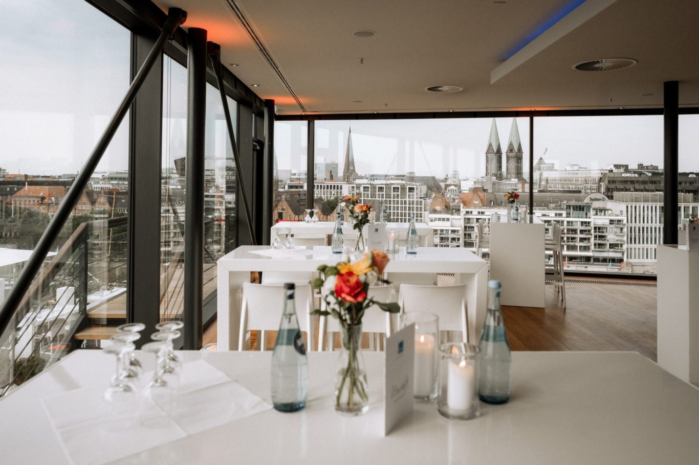 Eleganter Raum mit weissen Tischen und Blick auf die Stadt.