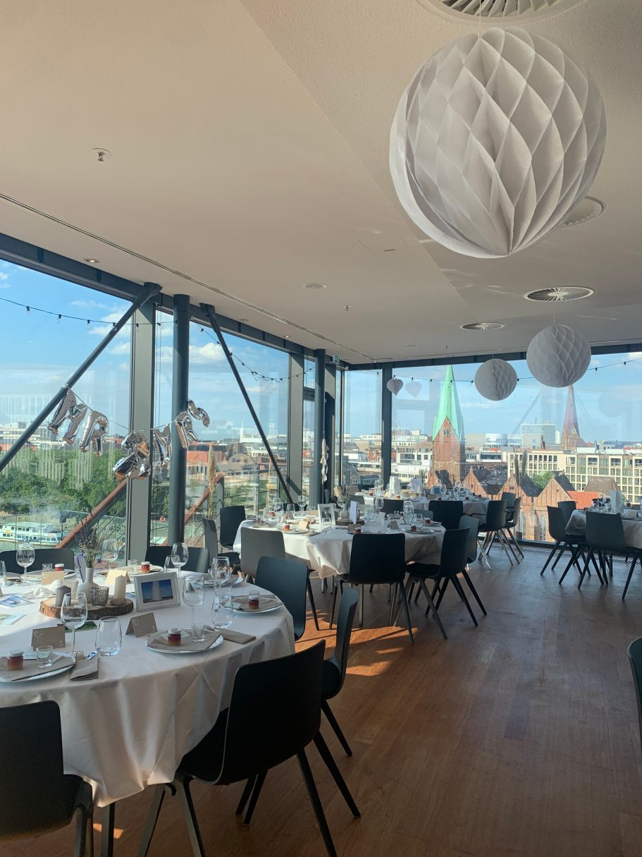 Elegantes Restaurant mit gedeckten Tischen und Blick auf die Stadt. Helle, moderne Einrichtung.